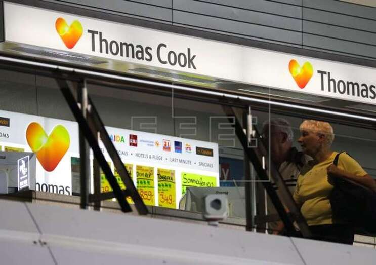 Dos pasajeros caminan frente a un escaparate de la empresa británica Thomas Cook (Foto Efe / Armando Babani)