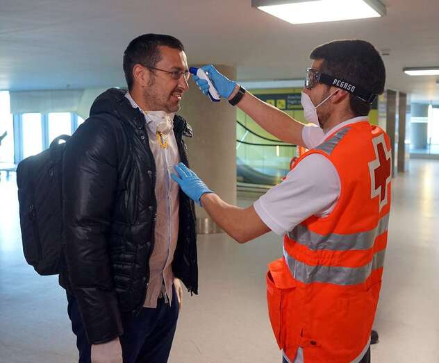 Un voluntario de Cruz Roja mide la temperatura a un pasajero en Gando (Foto Acfi Press)