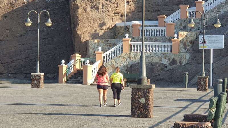 Dos jóvenes caminando esta mañana por el muelle de Melenara (Foto TA)
