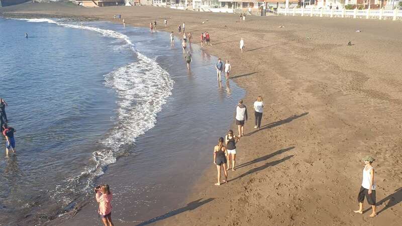 Vecinos de la costa paseando esta mañana por la arena de la playa de Melenara (Foto TA)