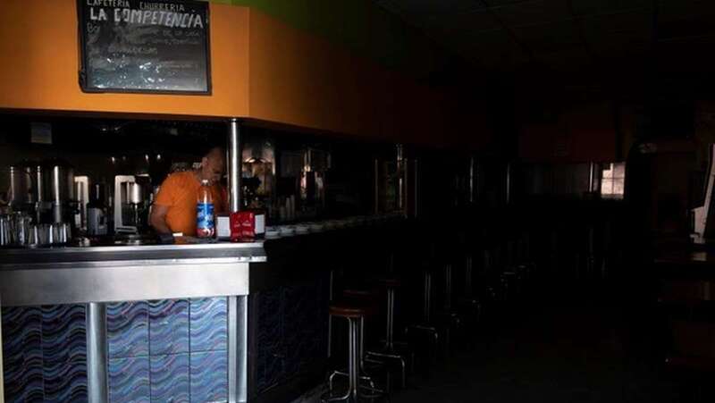 Un empleado de cafetería de Santa Cruz de Tenerife intenta trabajar a oscuras mientras espera que se restablezca el suministro eléctrico la isla (Foto EFE)