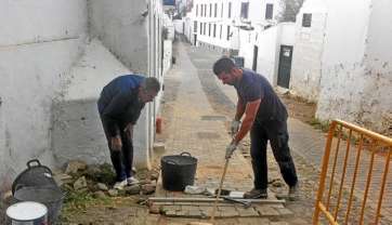 Imagen de dos de los operarios recolocando adoquines en el Callejón de La Fuente (Foto C7)