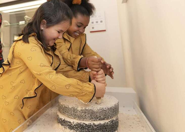 Niñas moliendo gofio en una actividad/TA.