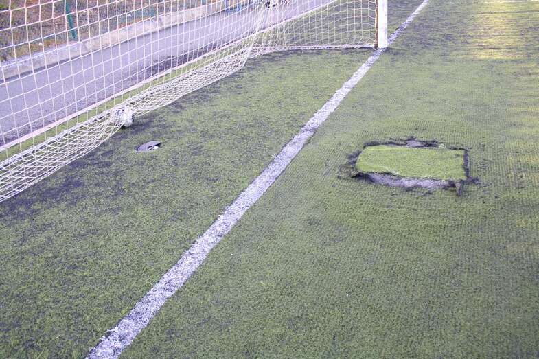El césped artificial está lleno de desperfectos y parches (Foto TA)