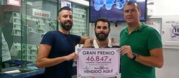 Trabajadores de la Administración de Loterías muestran el cartel indicativo del premio (Foto TA)