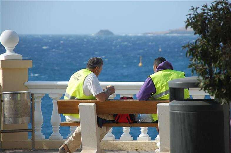 Operarios descansan en un banco de la plaza de Los Pinos, en Clavellinas (Foto TA)