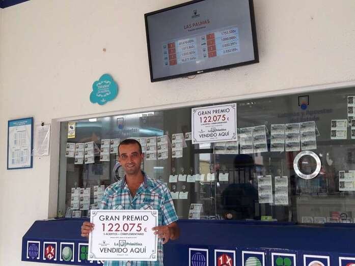 El empleado Roberto Sánchez muestra el cartel que certifica la venta del boleto ganador (Foto TA)