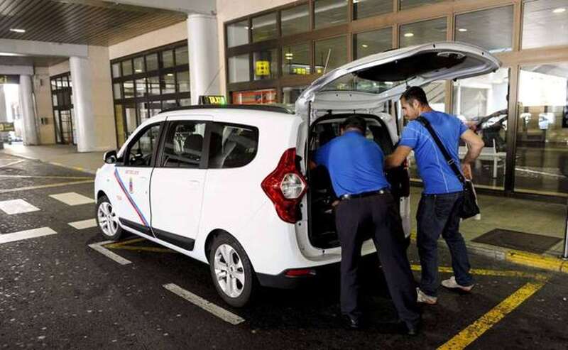 Un taxista ayuda a cargar en su vehículo las maletas de un pasajero del aeropuerto/Arcadio Suárez.