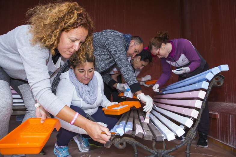 Miembros de la comunidad educativa y del colectivo Chrysallis pintando los bancos, esta mañana en el colegio teldense (Foto TA)