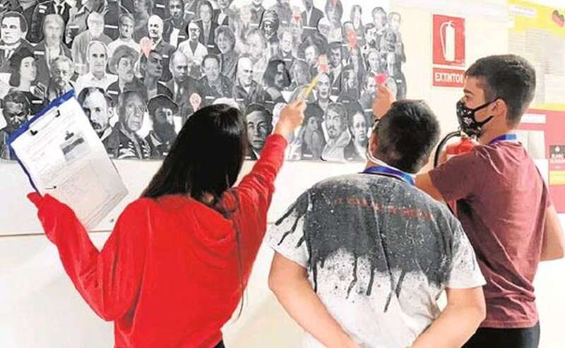 Varios de los alumnos, ayudados por los informes correspondientes, buscan pistas en el mural dedicado a las mujeres científicas y artistas.