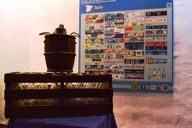 Botellas antiguas junto a uno de los paneles de etiquetas de agua (Foto TA)