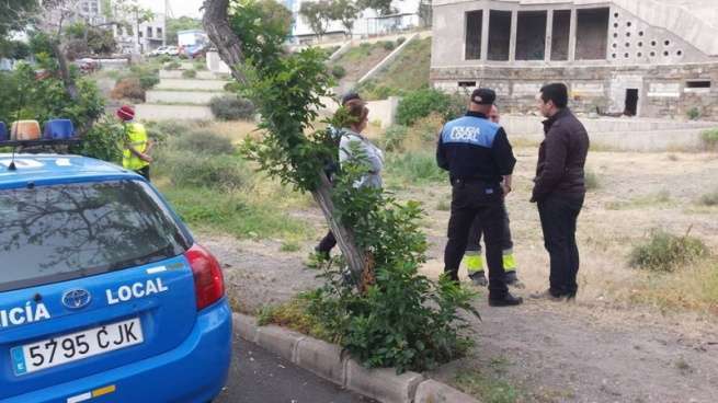 El concejal Alejandro Ramos con agentes de la Policía Local y vecinos, en el solar donde se encuentra el inmueble inacabado (Foto TA)