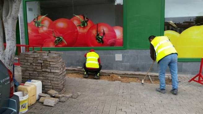 Operarios municipales arreglan el hundimiento de adoquines en una acera de Arnao (Foto TA)