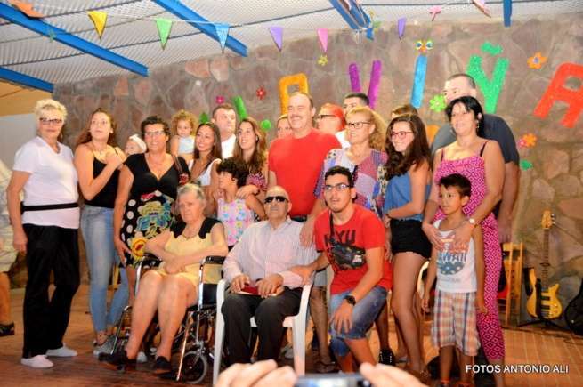 El pregonero, sentado en una silla y con gafas oscuras, con su familia, en el escenario de la plaza de La Viña (Foto Antonio Alí)