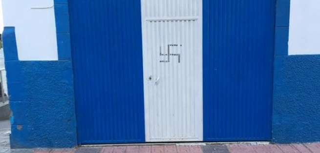 La cruz esvástica, emblema de los nazis, pintada en la puerta de acceso a la sede del PP Telde (Foto TA)