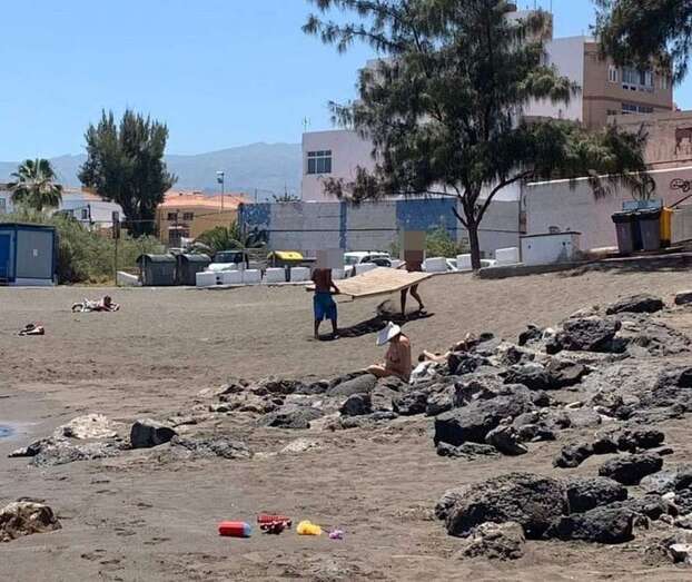 Dos usuarios usan tramos de la rampa de acceso a la arena para hacerse un solario individual (Foto TA)
