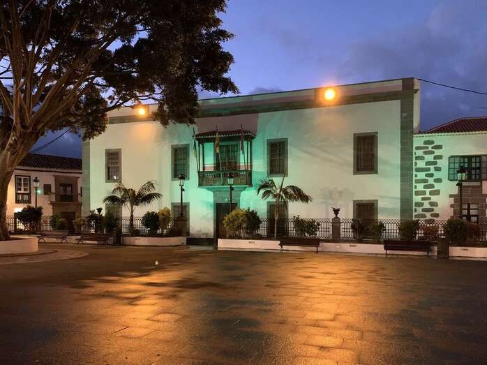 Imagen de la fachada principal de las Casas Consistoriales iluminada de verde/TA.