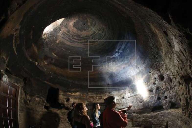 Julio Cuenca, el arqueólogo descubridor de Risco Caído explica la trayectoria del haz de luz que entra por la cueva en determinados momentos del año. EFE/Elvira Urquijo A.