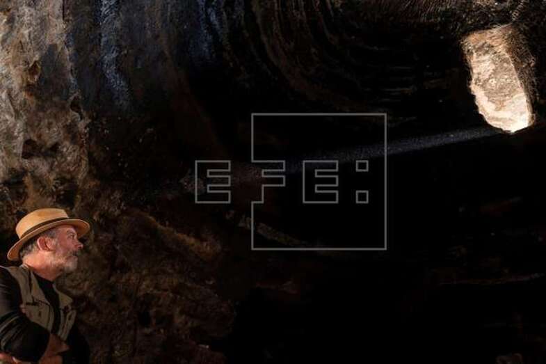 El haz de luz que entra por la abertura tallada en la cúpula de la cueva C6 de Risco Caído ilumina al arqueólogo Julio Cuenca (Foto EFE / Ángel Medina G.)