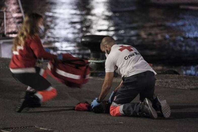 Sanitarios, voluntarios de la Cruz Roja y marineros de Salvamento reaniman sobre el suelo del puerto de Arguineguín a un niño pequeño que desembarcó de la patera localizada al sur de Gran Canaria con hipotermia severa/Ángel Medina (EFE)