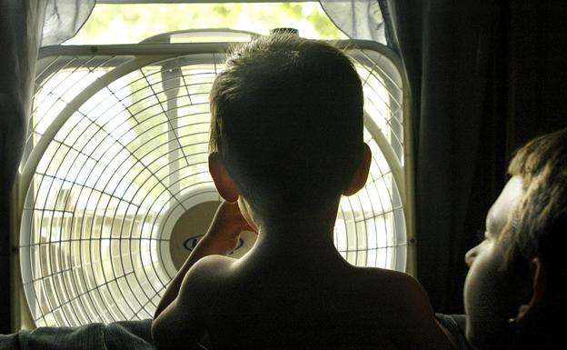 Niños alivian el calor frente a un ventilador en su casa (Foto AP)