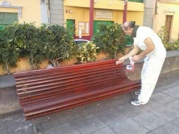 Un operario de Servicios Municipales barniza un banco de la plaza de Lomo Magullo (Foto TA)
