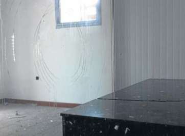 En primer plano, catafalco roto en dos piezas. Detrás, vitrina de cristal apedreada (Foto C7)