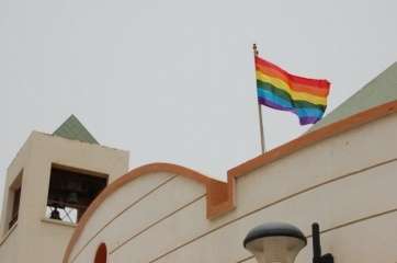 La bandera del movimiento LGTB, en lo alto de la fachada de la Parroquia de La Garita (Foto TA)