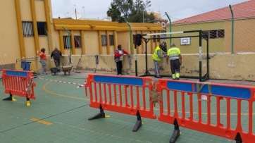 Operarios municipales en la cancha del CEIP Gregorio Chil y Naranjo de Las Huesas (Foto TA)