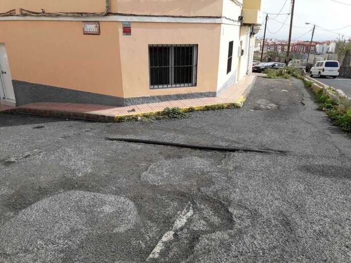 Una tubería asoma por el maltrecho asfalto de la calle Virtud, en el Valle de los Nueve (Foto TA)
