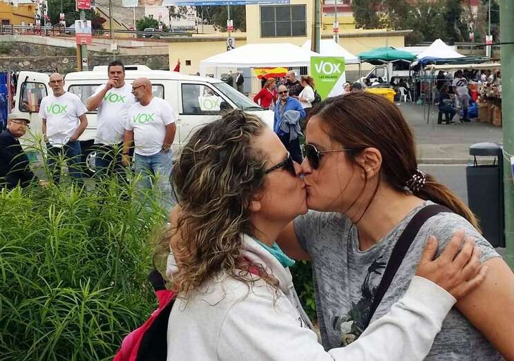 Esther González y Rosa Vega se besan ante la mirada de miembros de Vox, este domingo en el mercadillo de Jinámar (Foto TA)