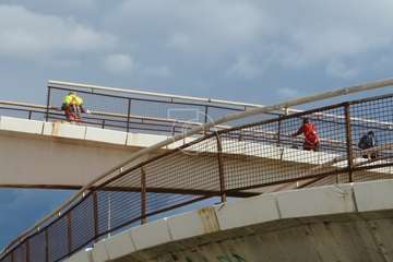 Operarios municipales retiran las vallas oxidadas de un paso elevado del vial costero de Telde/TA.