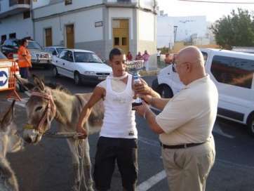 Juan Montesdeoca, hasta ahora presidente del Patronato, entrega un trofeo a un participante en una carrera de burros (Foto TA)