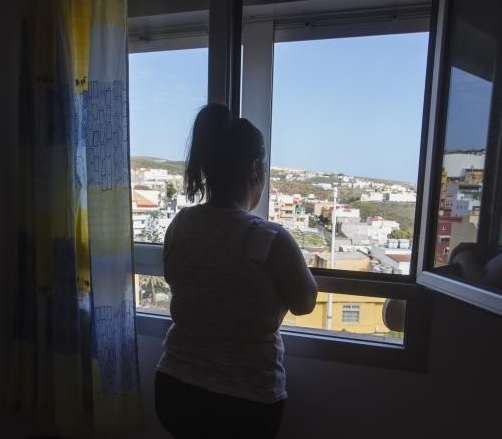 Pilar Ojeda, que prefiere ocultar su rostro por sus hijas, en la ventana de su casa en Telde. (Foto Borja Suárez/C7)