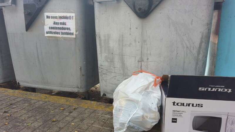 Cartel en un contenedores y basura depositada en la acera aun habiendo espacios libres en los depósitos (Foto TA)