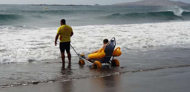 Uno de los usuarios es introducido en el agua con la ayuda de una silla móvil por un socorrista de Proactiva (Foto TA)