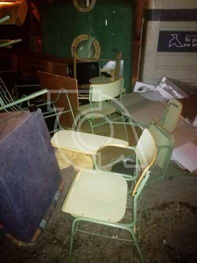 Pupitres y sillas depositados en la vía pública, junto al punto de recogida de residuos (Foto TA)