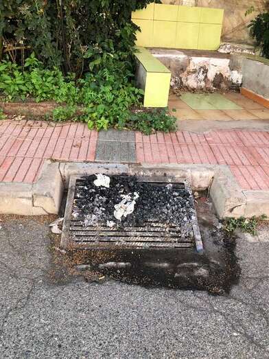 Restos de las brasas de un asadero sobre las rejillas de un desagüe de aguas pluviales (Foto TA)