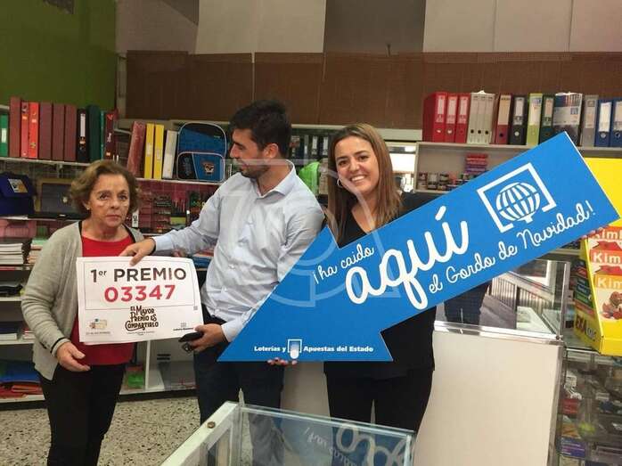 La propietaria del punto de venta de San Juan con el cartel del primer premio (Foto TA)