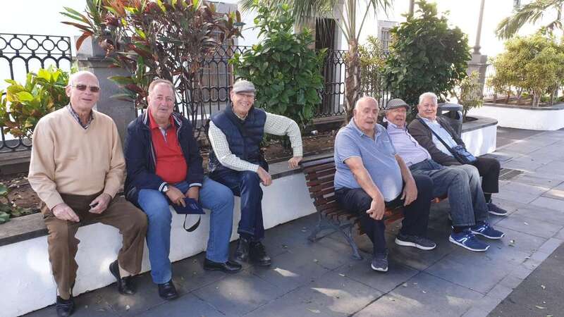 Grupo de tertulianos de la plaza de San Juan. Tres de ellos sentados en el parterre por la insuficiencia del único banco que hay en ese punto del parque (Foto TA)