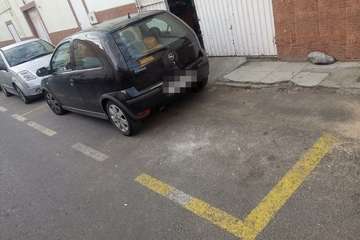 Coche aparcado en el vado de un almacén en una calle del casco de Jinámar/TA.