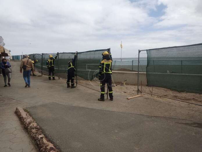 Los bomberos en la zona reponiendo en su lugar la valla de malla verde/TA.