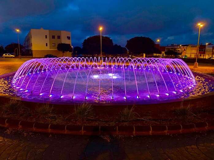 Fuente de la plaza de la urbanización residencial La Vega con los chorros iluminador de color violeta/TA.