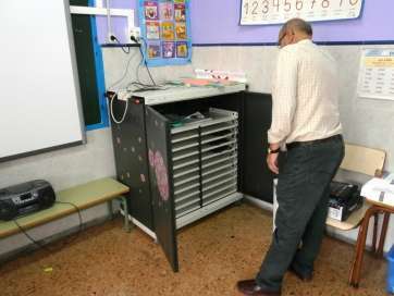 El director del colegio observa el mueble donde se guardaban los cinco ordenadores robados (Foto TA)