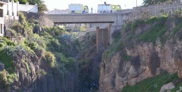Imagen de los bomberos en el puente y de los servicios de emergencia en el fondo del barranco donde está el cadáver (Foto TA)