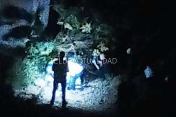 Agentes policiales junto al puente alumbran con linternas el lugar donde está el cadáver (Foto TA)