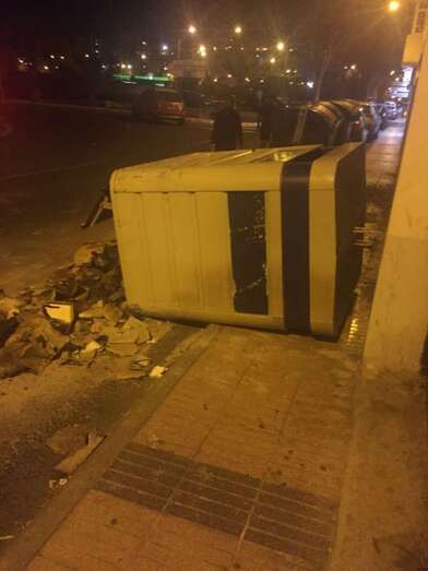 Contenedor metálico tirado y restos de los calcinados sobre la carretera y acera (Foto TA)