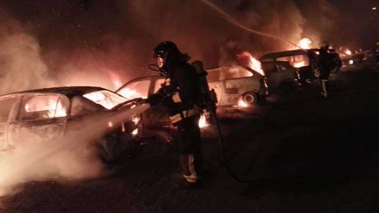 Bombero sofocando uno de los vehículos incendiados (Foto TA)