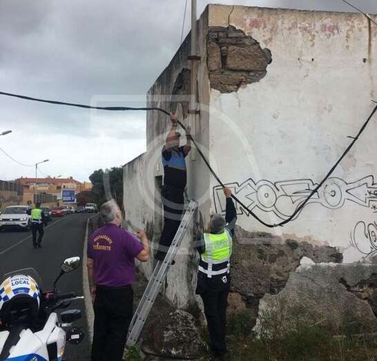 Un policía local  sujeta el cable de forma provisional hasta la llegada de los servicios (Foto TA)