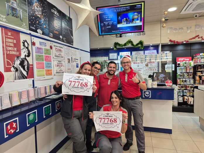 Empleados del negocio exhiben el cartel acreditativo de haber vendido un cuarto premio de la Lotería de este domingo/TA.